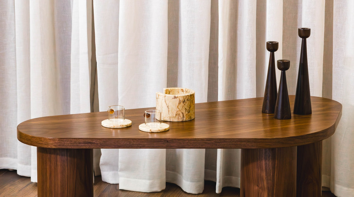 The ORGANIC coffee table in solid walnut with marble accessories and turned candle holders, against linen curtains